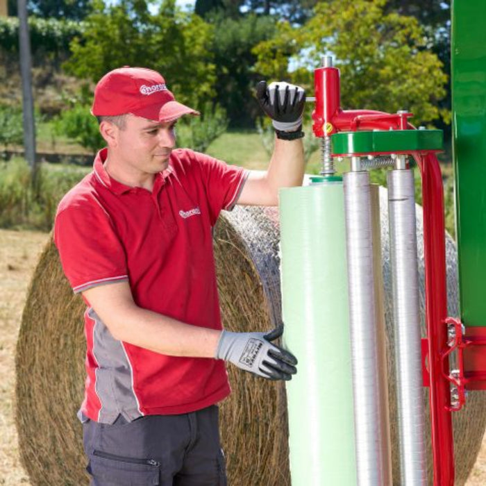 Operator standing beside Enorossi BW bale wrapper after wrapping