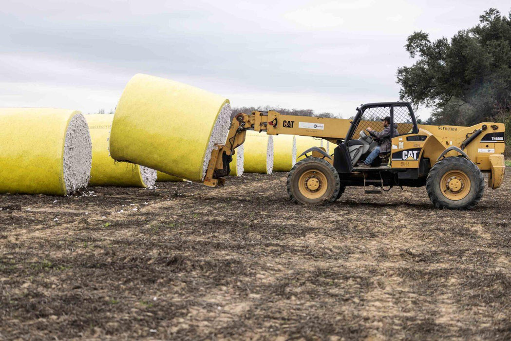 Round cotton module being handled with telehandler during harvest operations